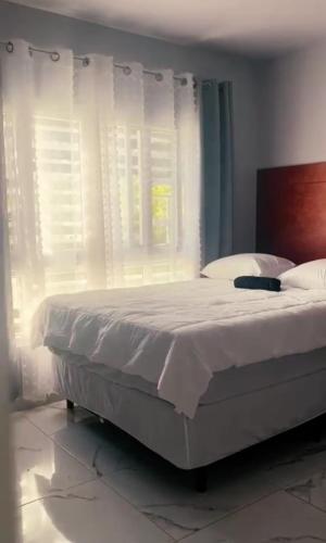 una camera da letto con un letto con lenzuola bianche e una finestra di Casa Chavez en Tela a Tela