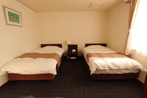 a hotel room with two beds in a room at Yufuin Hotel Shuhokan in Yufuin