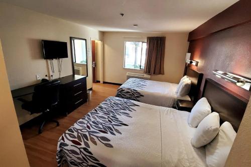 Habitación de hotel con 2 camas y escritorio en Sacramento Inn & Suites en Sacramento