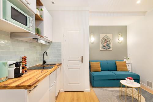 Il comprend une cuisine et un salon doté d'un canapé bleu. dans l'établissement Guestrust - Arc de Triomphe Green, à Paris