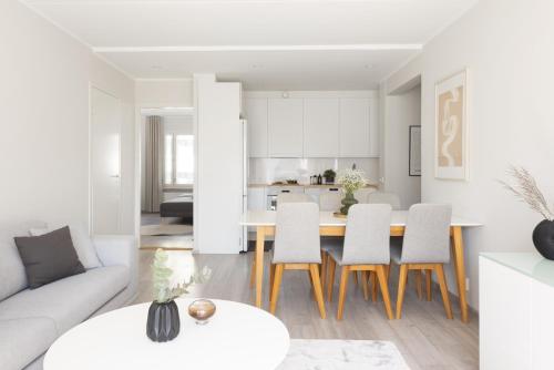 una sala de estar blanca con mesa y sillas en Stunning design apartment with sauna & free parking, en Helsinki