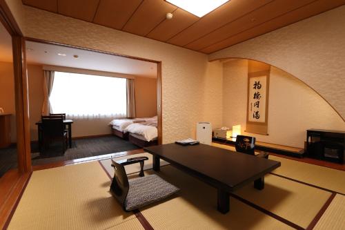 ein Wohnzimmer mit einem Tisch und einem Bett in der Unterkunft Yufuin Hotel Shuhokan in Yufu