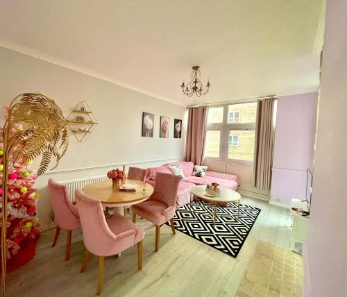 a living room with pink furniture and a table and chairs at Stylish Pink Oasis in Wimbledon in London