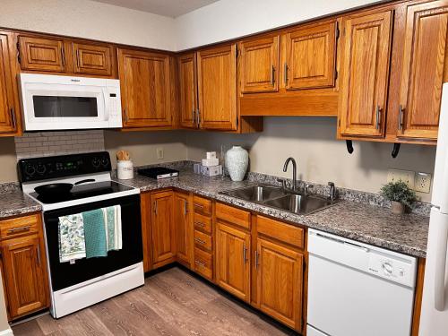 a kitchen with wooden cabinets and white appliances at Unwind in Tranquil Style - Spacious 3-Bed Haven in University Place