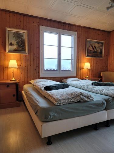 Duas camas num quarto com paredes de madeira e duas janelas em Chalet Nature Park "Apartment Thun" - Self Check-in em Thun