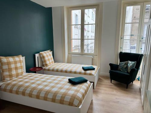 une petite chambre avec deux lits et une chaise dans l'établissement 24 CHIC & COSY GRAND APPART 88m2 PARKING GRATUIT HYPERCENTRE NETFLIX, à Saint-Étienne