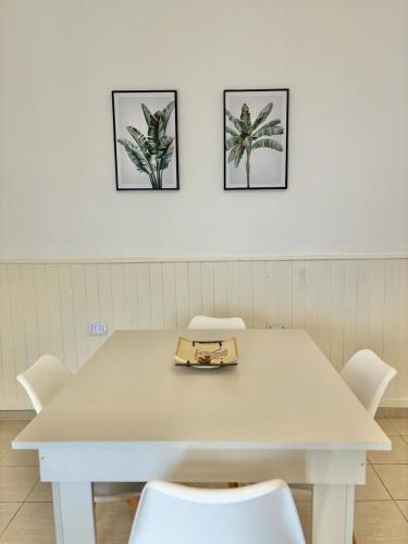 a white table with white chairs and three pictures on the wall at Casa Blanca 2 in Santiago del Estero