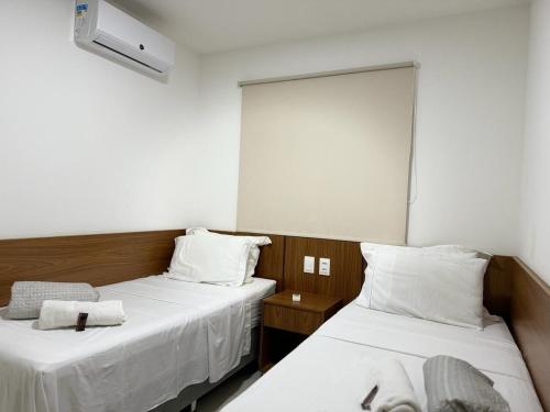 a room with two beds with white sheets at Apto c/vista próx a faculdade /hospitais PC2302 in Goiânia