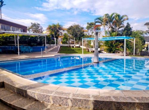 a swimming pool in a resort with a checkered floor at Hotel y Cabañas Rio Mayo in Chachagüí