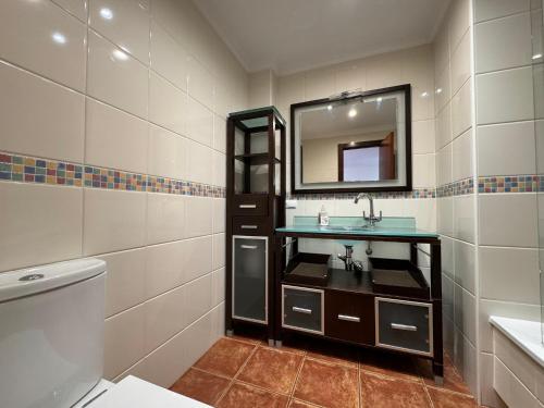 uma casa de banho com um lavatório, um espelho e um WC. em Alquilaencanarias Sotavento Paradise em Granadilla de Abona