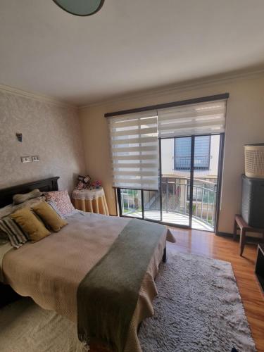 a bedroom with a large bed and a large window at Comodidad y Elegancia in Cochabamba