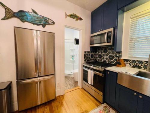 a kitchen with a stainless steel refrigerator and blue cabinets at Newly remodeled bungalow near downtown Brenham in Brenham