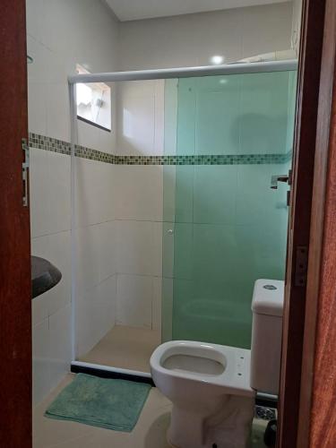 La salle de bains est pourvue de toilettes et d'une douche en verre. dans l'établissement Lindo AP inteiro de um quarto próximo a praia., à Vila Velha