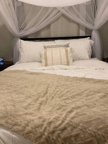 een wit bed met een baldakijn en kussens erop bij Be our guest BOHO 2.0 in Charlotte