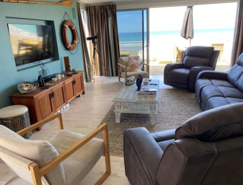 a living room with a couch and a tv at Ultimate Beach Front in Waimarama