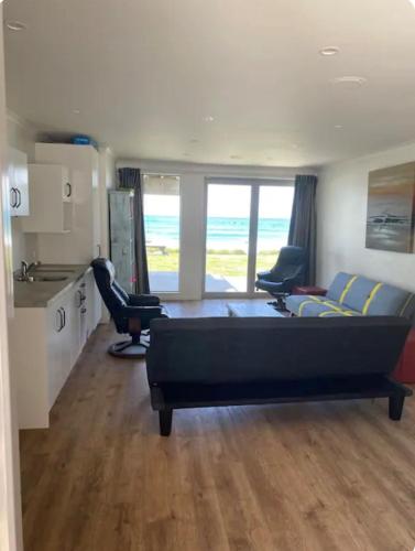 a living room with a couch and a table and chairs at Ultimate Beach Front in Waimarama