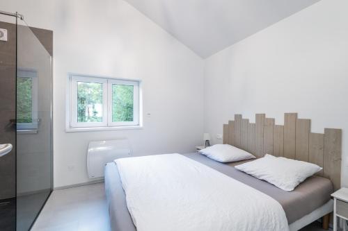 RochessonにあるLe Petit Bouchot & Jacuzzi privatif proximité Gerardmer & La Bresseの白いベッドルーム(大型ベッド1台、窓付)