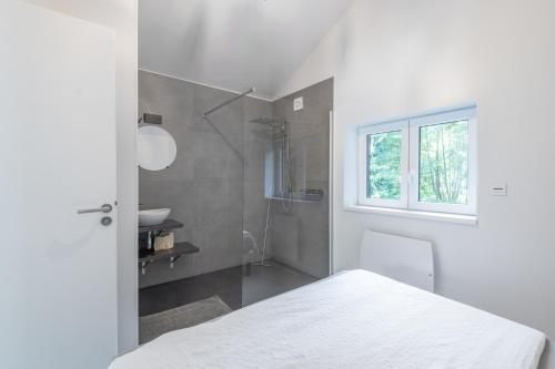 ein Badezimmer mit einem weißen Bett und einem Waschbecken in der Unterkunft Le Petit Bouchot & Jacuzzi privatif proximité Gerardmer & La Bresse in Rochesson