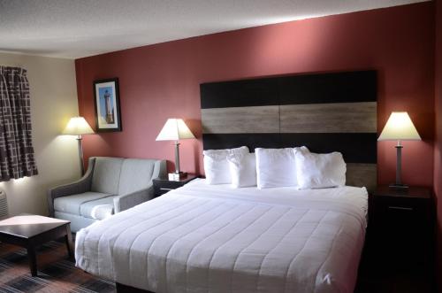 a hotel room with a large bed and a chair at Baymont by Wyndham Waupun in Waupun