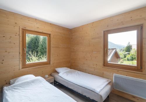 duas camas num quarto com duas janelas em Chalets du Bouchot & Jacuzzi privatif proximité Gerardmer & La Bresse em Rochesson