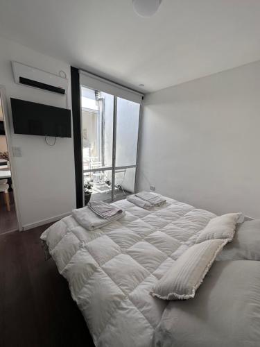 a white bedroom with a large bed and a large window at PATAGONIA FLAT in Esquel