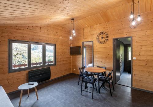 a room with a table and chairs and a clock at Chalet du Faubourg & Jacuzzi, proximité Gerardmer & La Bresse in Rochesson