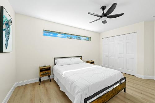 1 dormitorio blanco con 1 cama y ventilador de techo en Recently Remodeled Mins from beach+Putting Green, en Boynton Beach