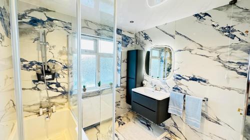ein Bad mit einer Dusche, einem Waschbecken und einem Spiegel in der Unterkunft Modern Great West 6 Bed Large house with Parking & WorkSpace in Brentford