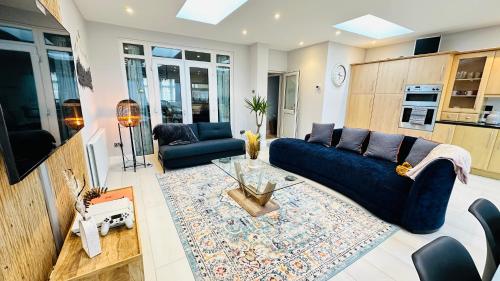 ein Wohnzimmer mit einem blauen Sofa und einem Teppich in der Unterkunft Modern Great West 6 Bed Large house with Parking & WorkSpace in Brentford