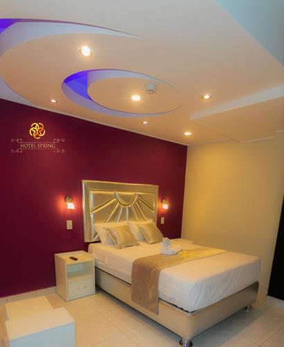 1 dormitorio con 1 cama con pared morada en Hotel Spring, en Huánuco