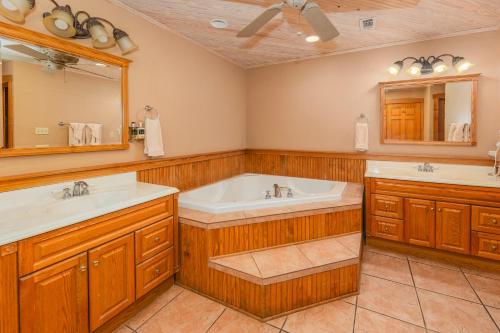 een badkamer met 2 wastafels, een bad en een spiegel bij Country Inn Cottages in Fredericksburg