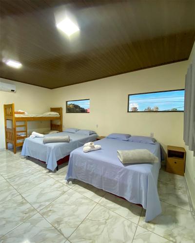 Cette chambre comprend 2 lits, une table et 2 fenêtres. dans l'établissement Bonito Suítes, à Bonito