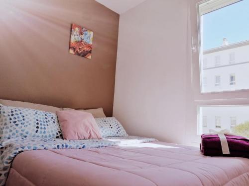1 cama con almohadas rosas y azules y ventana en Piso nuevo y moderno, en Santiago de Compostela