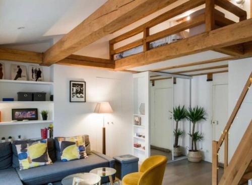 uma sala de estar com um sofá azul e tectos em madeira em Lovely Flat Luxembourg Garden em Paris