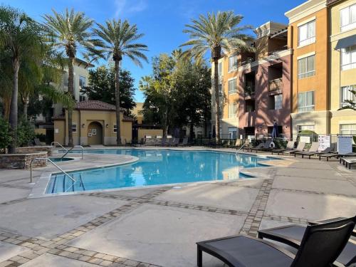 a large swimming pool with chairs and palm trees at Luxury Modern Condo 3-min from Six Flags w/PS5, 1GB Fast Wi-fi Kingbed in Santa Clarita