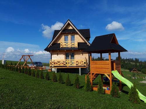 a house with a slide and a playground at Domki Tatrzański Przystanek in Białka Tatrzanska