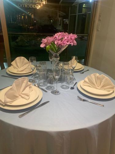 a table with plates and a vase of pink flowers at Hotel Los Rios in Guácimo