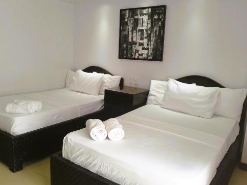 two beds in a room with white sheets and pillows at YCL HOTEL BORACAY in Boracay