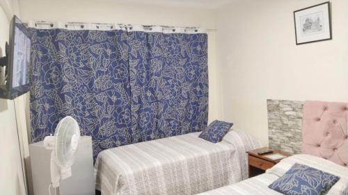 een kamer met 2 bedden en een blauw gordijn bij Hostal Donde Gabriel in Chillán