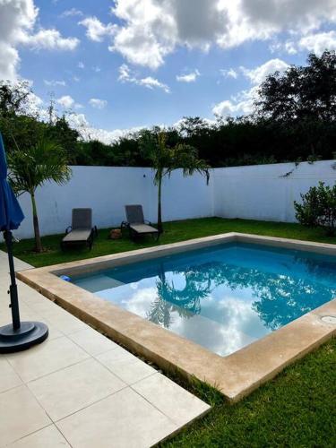 a small swimming pool in a yard with two chairs at Residencia con ALBERCA y JARDÍN privado in Cholul