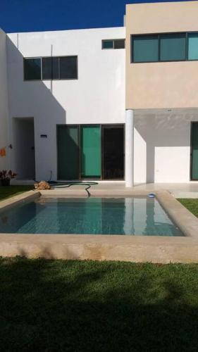 a building with a swimming pool in front of a house at Residencia con ALBERCA y JARDÍN privado in Cholul