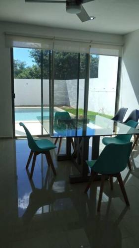 a dining room with a glass table and chairs at Residencia con ALBERCA y JARDÍN privado in Cholul