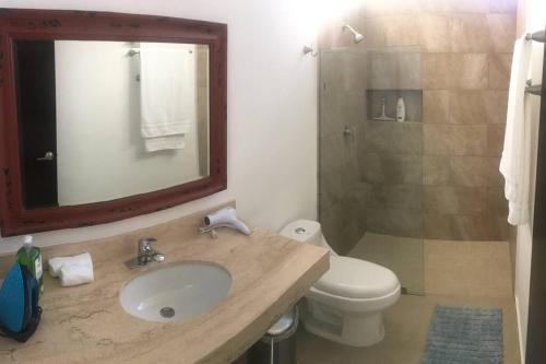 a bathroom with a sink and a toilet and a mirror at Residencia con ALBERCA y JARDÍN privado in Cholul