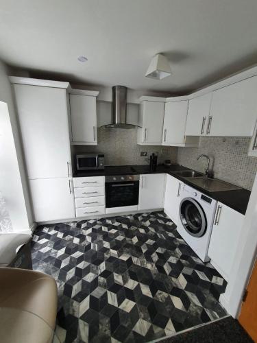 eine Küche mit weißen Schränken und einem karierten Boden in der Unterkunft Quiet 2 bedroom flat in Darlington with free parking, wi-fi and more in Darlington
