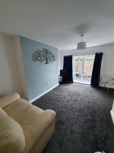 ein Wohnzimmer mit einem Sofa und einem Baumbild an der Wand in der Unterkunft Quiet 2 bedroom flat in Darlington with free parking, wi-fi and more in Darlington