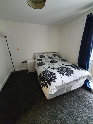 Schlafzimmer mit einem Bett mit einer schwarzen und weißen Bettdecke in der Unterkunft Quiet 2 bedroom flat in Darlington with free parking, wi-fi and more in Darlington