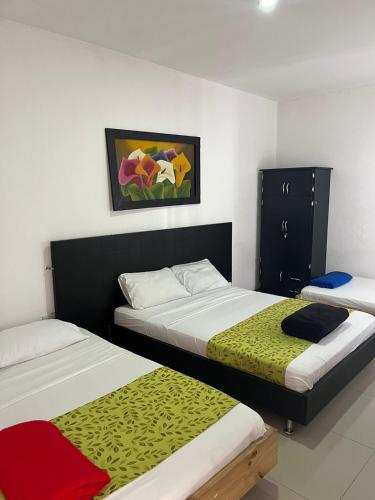 a bedroom with two beds and a painting on the wall at Hotel El Jardín Cafetero Armenia in Armenia