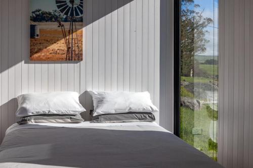a bedroom with a bed and a large window at Bedervale Tiny in Braidwood
