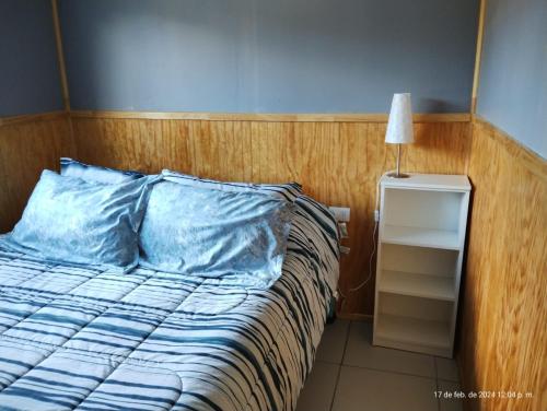 a bed with a blue pillow and a night stand at Cabaña Precordillera Cunco in Cunco