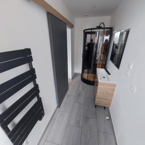 - un couloir avec une salle de bains pourvue d'un lavabo et d'un miroir dans l'établissement Appartement centre Merville, à Merville